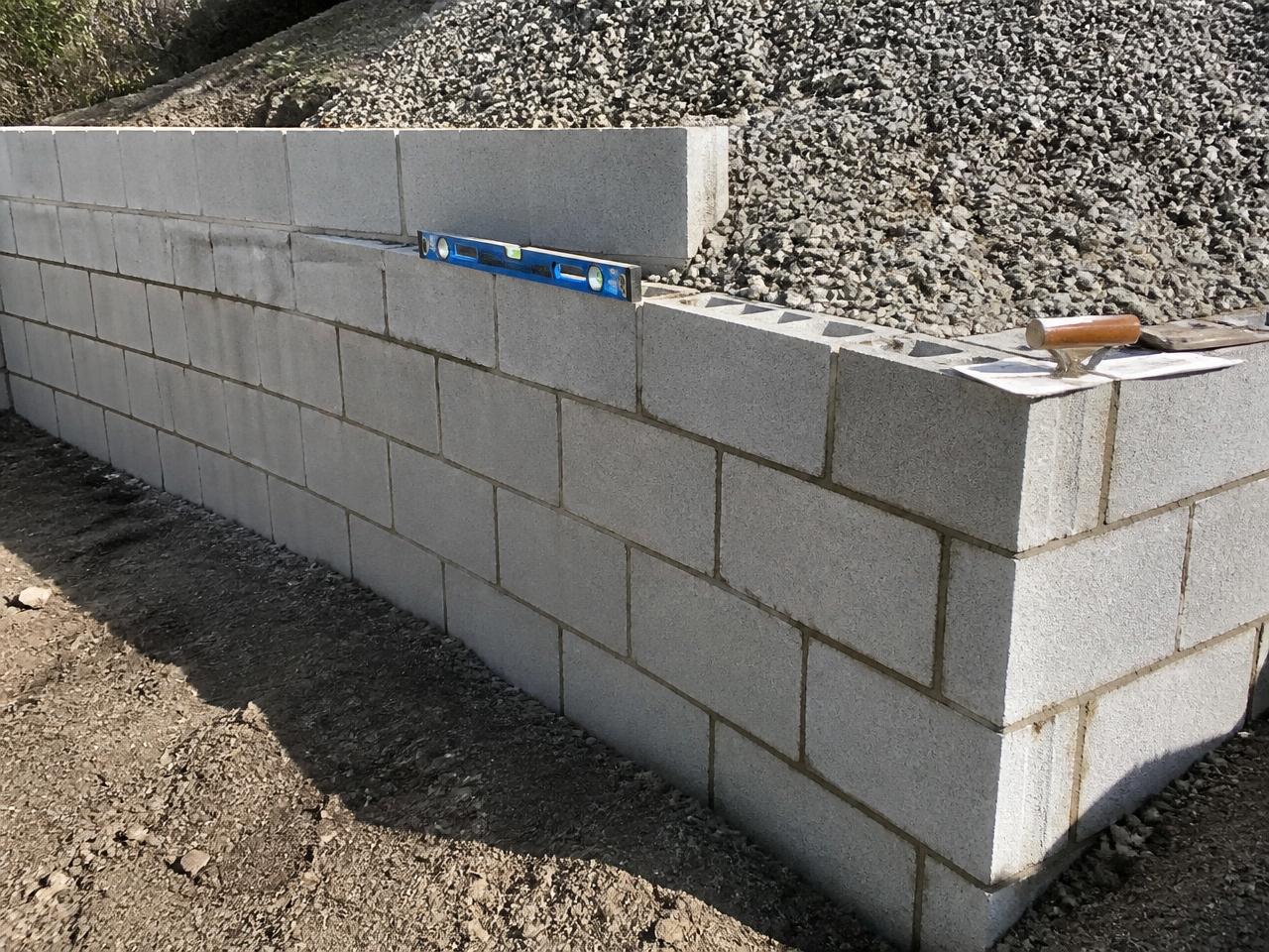 Concrete block wall under construction with level resting on top course