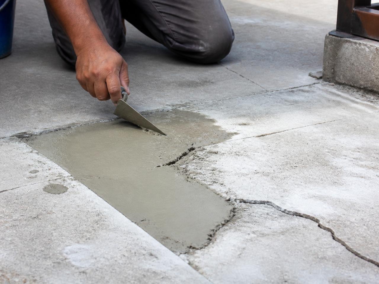 Worker patching a cracked concrete slab with fresh mortar